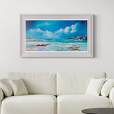 Framed beach scene art above a white sofa