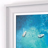 Framed artwork of two boats on a blue ocean with a white frame.