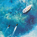 Two jet skis with water trails next to a sailboat on a blue water surface