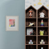 Wooden shelf with toys and books against a light blue wall with a framed picture.