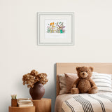 Framed artwork above a bed with a teddy bear and decorative items.