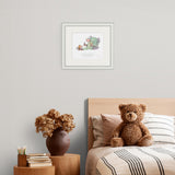Framed artwork above a bed with a teddy bear and decorative items.