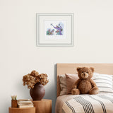 Framed artwork above a bed with a teddy bear and decorative items.