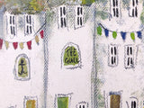 A close-up of a textured painting depicting white buildings with black window outlines, green door and wall accents, and colorful bunting flags in red, yellow, blue, and green.