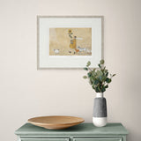 framed artwork on a plain wall above a side table and a vase.