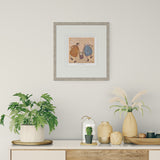 Decorative setting with plants, vases, and a framed picture on a wall.
