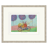 Framed artwork of a couple on a bicycle with a dog, under purple balloons.