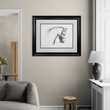 Framed black and white artwork on a beige wall above a gray sofa.