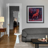 abstract painting of red horse on dark background with black and gold frame on a wall above a grey sofa and wooden table