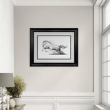 Framed black and white artwork of a horse on a wall in a room with a window and lamp.