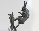 Bronze sculpture of a leaping hare on a white background