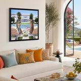 Living room with a white sofa, colourful pillows, and a framed picture of two people by a pool.