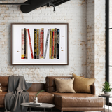 framed artwork of bookends on white brick wall above a tan leather sofa.