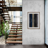 Modern interior with wooden staircase and framed artwork on a concrete wall.