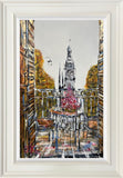 Framed artwork of a cityscape with a clock tower and street scene.