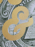 A close-up of a large gold ampersand symbol with a glittery texture, layered over a green and white illustrated background resembling currency or an engraving.