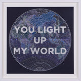 Framed world map with 'You light up my world' text on a dark background