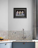 Kitchen with a framed picture of cupcakes on the wall above a sink.