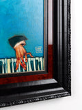 Framed artwork of a hand with a black glove holding a red object against a blue background.
