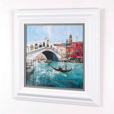 side view of framed cityscape artwork of venice water with boat and buildings surrounding on plain white wall