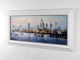 Framed artwork of a city skyline with a river, displayed on a white wall.