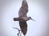 Sculpture of brown bird with wings spread on a white background