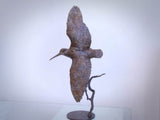 Bronze sculpture of a bird in flight on a white background