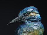 Close-up of a detailed ceramic or stone sculpture of a kingfisher against a black background