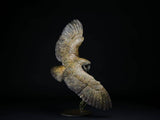 Statue of an owl in flight against a black background