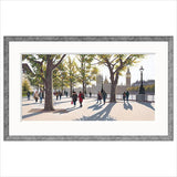 Framed artwork of a cityscape with people walking on a sidewalk, trees, and a building in the background. Jo Quigley limited edition art print