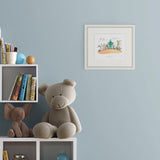 Children's room with teddy bear, elephant, books, and framed artwork on a light blue wall.
