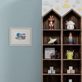 framed illustration of a child mixing ingredients in a large metal pot surrounded by bottles on blue wall next to shelves of kids toys.