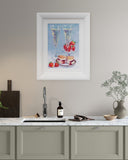 Framed artwork of champagne glasses and strawberries on a kitchen wall