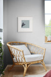 artwork of black cat peeking from corner hung up next to chair