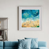 Framed artwork of a beach scene with boats on a wall above a blue sofa.