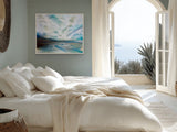 A framed landscape painting with blue, white, and gray tones hangs on a wall