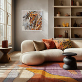 A framed horse painting hangs on a gray wall above a cream curved sofa in a styled living room with patterned pillows, a rug, shelving, and side tables.