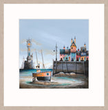 A framed art print featuring a whimsical coastal village scene with a small orange boat on the shore, colorful houses, a lighthouse, and a wooden dock under a pale blue sky.
