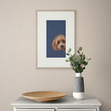 Framed artwork of a dog on a wall above a table with a vase and plate.